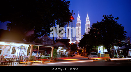 Il tramonto e la notte scende come le Torri Petronas incombono su di Kampung Baru nella città di Kuala Lumpur in Malesia in Estremo Oriente Asia sud-orientale. Città Travel Foto Stock