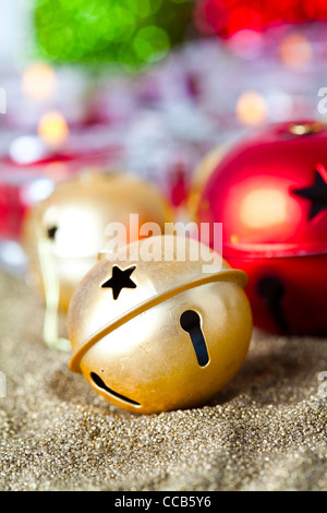 Close-up di oro e rosso jingle bell baubles di Natale con le candele Foto Stock