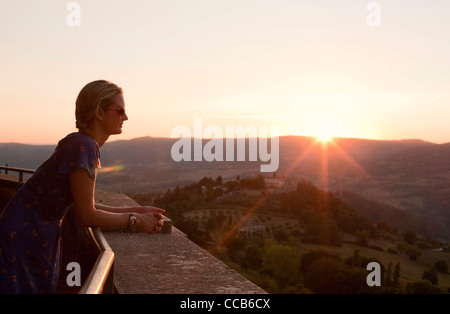 Una giovane donna si affaccia sulla campagna come il sole tramonta. Todi, Umbria, Italia. Foto Stock