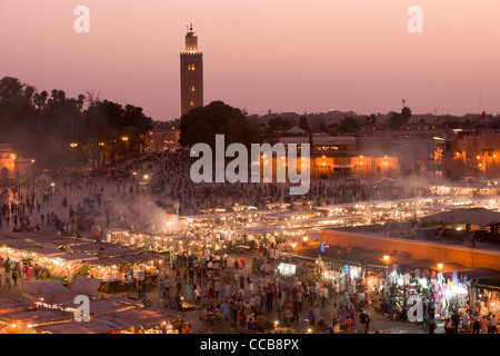 Affacciato sulla alfresco mercato alimentare in Djemaa el Fna al tramonto, con la Moschea di Koutoubia dietro a Marrakech, Marocco Foto Stock