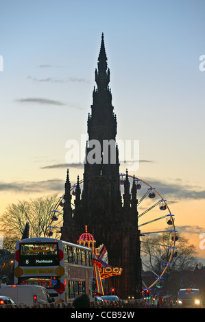 Monumento di Scott affiancato da Natale grande ruota panoramica Ferris in Princes Street Gardens, Edimburgo, Scozia, al crepuscolo Foto Stock