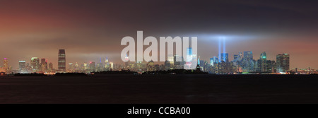New York City Manhattan skyline del centro panorama di notte con la statua della libertà e i fasci di luce Foto Stock