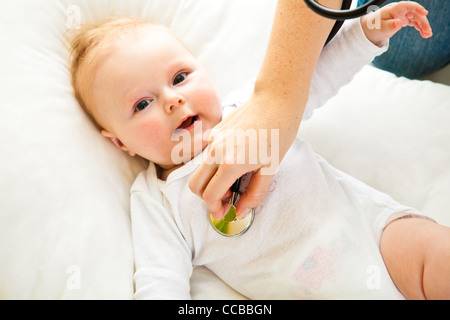 Madre ausculating infant Baby girl su bianco Foto Stock