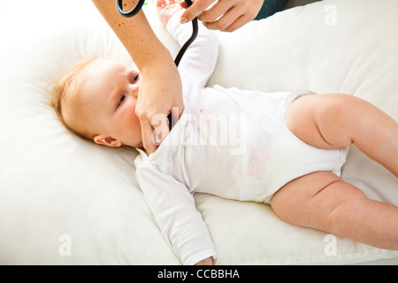 Madre ausculating infant Baby girl su bianco Foto Stock