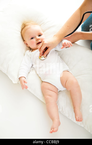 Madre ausculating infant Baby girl su bianco Foto Stock