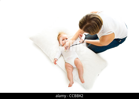 Madre ausculating infant Baby girl su bianco Foto Stock