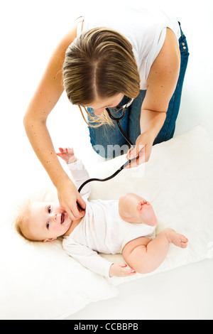 Madre ausculating infant Baby girl su bianco Foto Stock