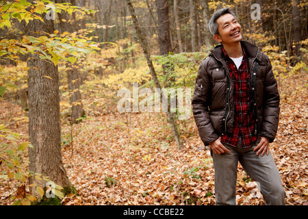 Uomo a camminare attraverso la foresta con foglie modifica dei colori Foto Stock