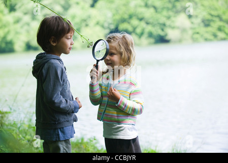 Bambini che giocano con lente di ingrandimento all'aperto Foto Stock