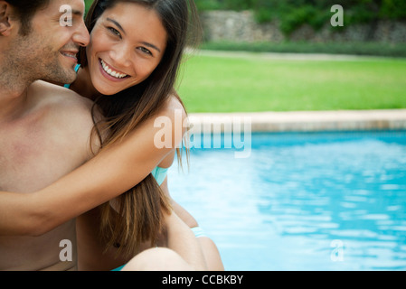 Giovane abbracciando da piscina, ritratto Foto Stock