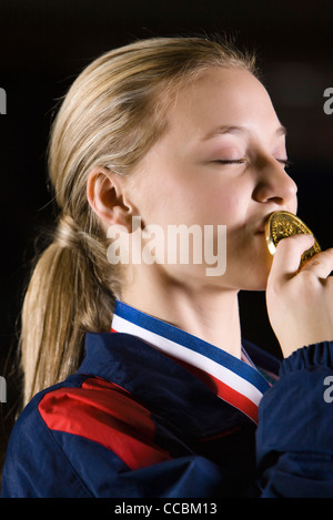 Atleta femminile baciare la medaglia d'oro Foto Stock