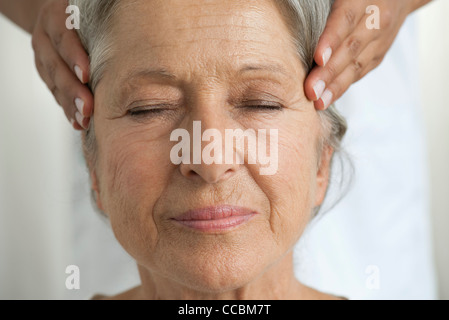 Senior donna avente i suoi templi massaggiato, ritagliato Foto Stock