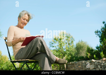 Senior donna libro lettura all'aperto Foto Stock