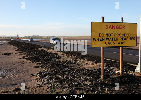 Avviso di pericolo e di automobili che attraversano la strada rialzata a St Mary's Island, North East England Regno Unito Foto Stock