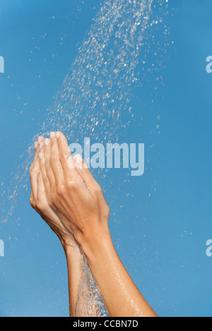 Le mani sotto gli spruzzi d'acqua Foto Stock