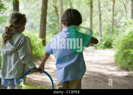 Bambini passeggiate nel bosco insieme con butterfly net e benna Foto Stock