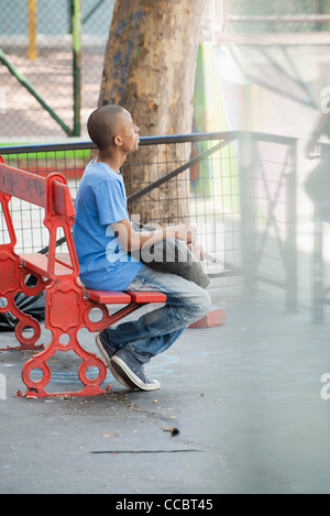 Giovane uomo seduto su un banco di lavoro Foto Stock