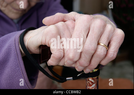 Donna anziana le mani tenendo un bastone da passeggio Foto Stock