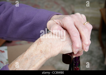 Donna anziana le mani tenendo un bastone da passeggio Foto Stock