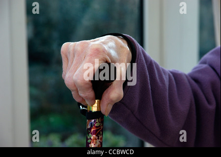 Donna anziana le mani tenendo un bastone da passeggio Foto Stock