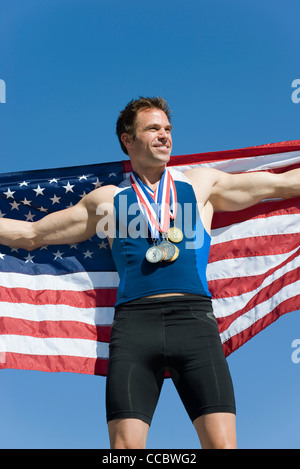 Atleta maschio sul vincitore podio, mantenendo la bandiera americana Foto Stock