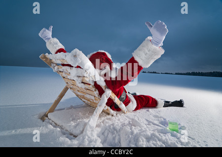 Santa Claus relax su un lettino nella neve durante la notte Foto Stock