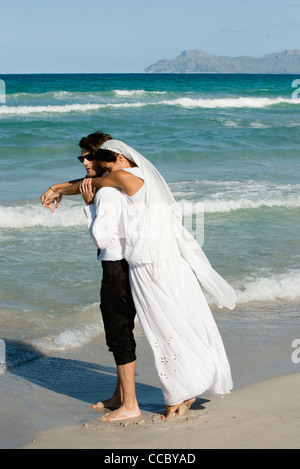 Sposa e lo sposo abbracciando in spiaggia Foto Stock