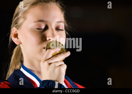 Atleta femminile baciare la medaglia d'oro, ritratto Foto Stock