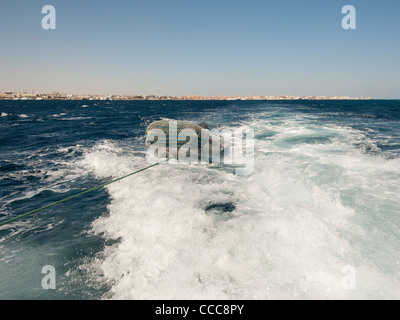 Piccola imbarcazione gonfiabile che viene trainato in scia di un grande yacht Foto Stock