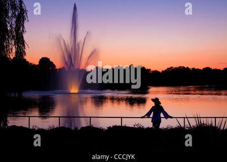 Silhouette di donna guardando una bella fontana al crepuscolo. Foto Stock