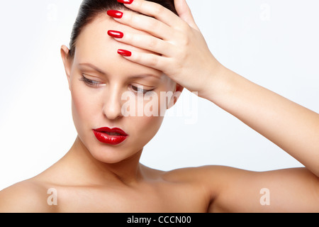 Posh donna con labbra rosse e le unghie di toccare la fronte Foto Stock