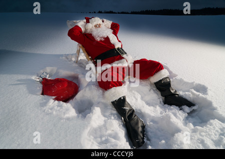 Santa Claus relax su un lettino nella neve durante la notte Foto Stock