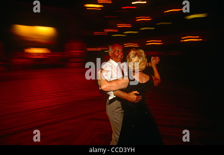 Un anziano pensionato ballo di coppia sulla vasta ma oscuramente accesa pista da ballo a Blackpool Tower Ballroom, Inghilterra. Foto Stock