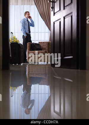 Caucasica adulto medio imprenditore parlando con un telefono mobile in camera in hotel durante il viaggio di affari Foto Stock