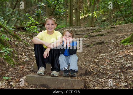 Due ragazzi (fratelli) foresta Sentiero escursionistico seduti sulle scale Foto Stock