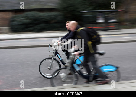 Due ciclisti di Boris bikes - un sorpasso di altri che si stava appena cominciando a spostare su off Foto Stock