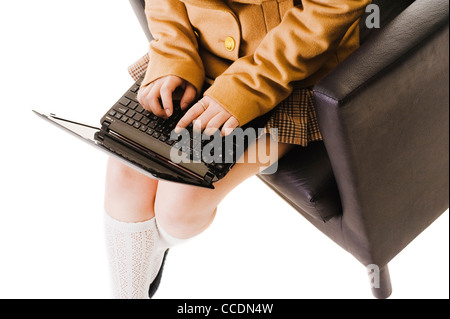 Primo piano di una femmina di studente cinese a lavorare su un laptop mentre è seduto in una sedia in pelle. Foto Stock