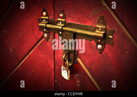 Rusty Vecchia serratura, fermo sul legno della porta chiusa con un lucchetto moderno. Foto Stock