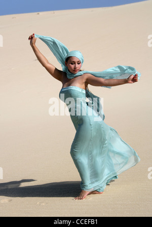 Indonesian Ragazza in un abito color turchese in posa sulle dune di sabbia, Fuerteventura, Isole Canarie, Spagna. Foto Stock