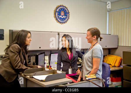 Femmina di tre agenti FBI discutere un caso in Santa Ana CA, office. Nota Filipino-American in centro e FBI logo sul muro. Rilasciato Foto Stock