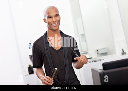 Sorridente parrucchiere maschio holding di forbici e spazzola per capelli Foto Stock