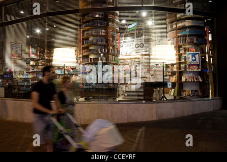 Coppia giovane con passeggino a piedi di notte a Tel Aviv, passato Steimatsky's book store. Foto Stock