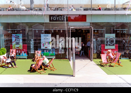 Per coloro che godono di un sole estivo seduto nella sedia a sdraio al di fuori della libreria Foyles a Southbank Lambeth Londra Inghilterra REGNO UNITO Foto Stock