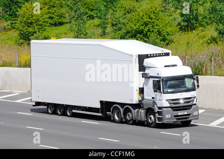 E il lato anteriore del bianco pulito non marcati hgv consegna autocarro autocarro articolato e forma aerodinamica rimorchio percorrendo l autostrada M25, Essex England Regno Unito Foto Stock