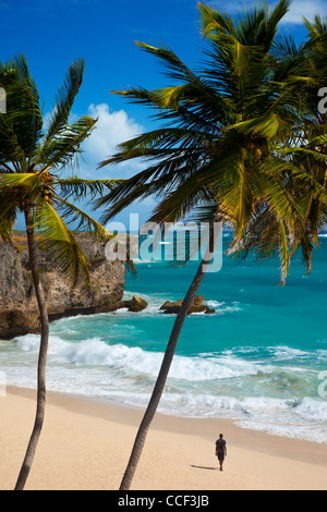 Lone uomo cammina lungo la spiaggia di fondo baia sulla costa sud-est di Barbados, West Indies Foto Stock