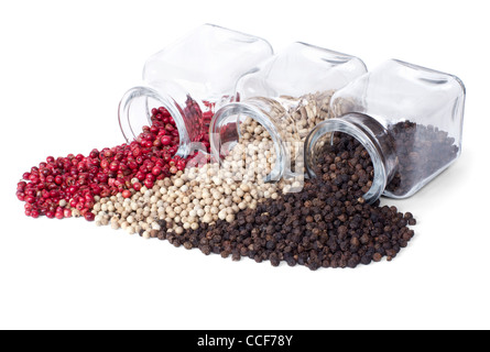 Nero, bianco e pepe rosa sparsi su uno sfondo bianco da bottiglie in vetro Foto Stock
