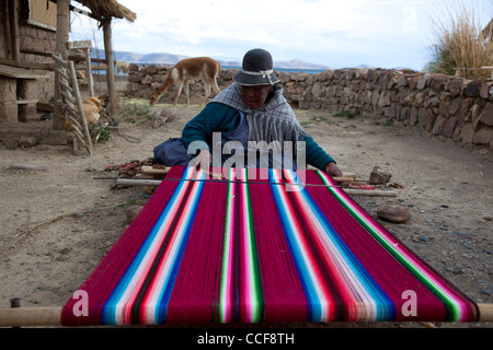 Una donna Aymara tesse su un tradizionale telaio a mano in Huatajata sul Boliviano della riva del lago Titicaca. Foto Stock