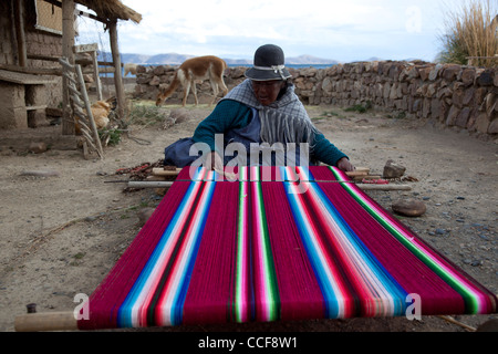 Una donna Aymara tesse su un tradizionale telaio a mano in Huatajata sul Boliviano della riva del lago Titicaca. Foto Stock