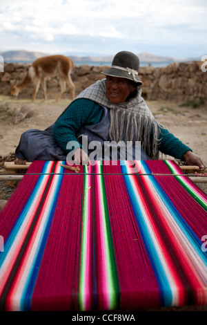 Una donna Aymara tesse su un tradizionale telaio a mano in Huatajata sul Boliviano della riva del lago Titicaca. Foto Stock