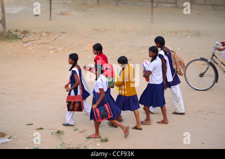 Ragazze indiane adolescenti in uniforme scuola/università che tengono borse e libri camminando insieme su strada in campagna Foto Stock